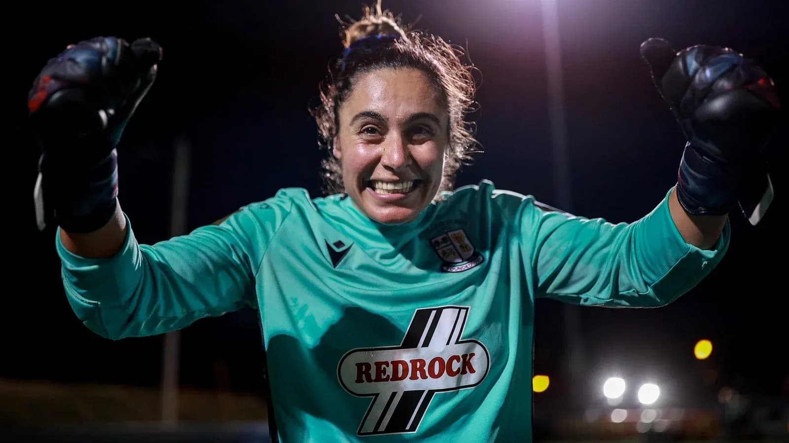Goalkeeper celebrating with raised fists at night