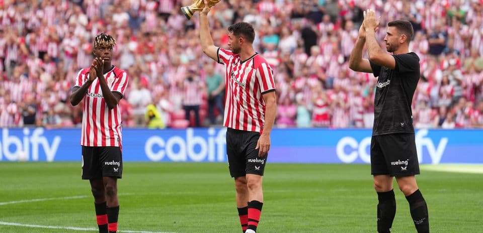 Player holding trophy with teammates applauding fans