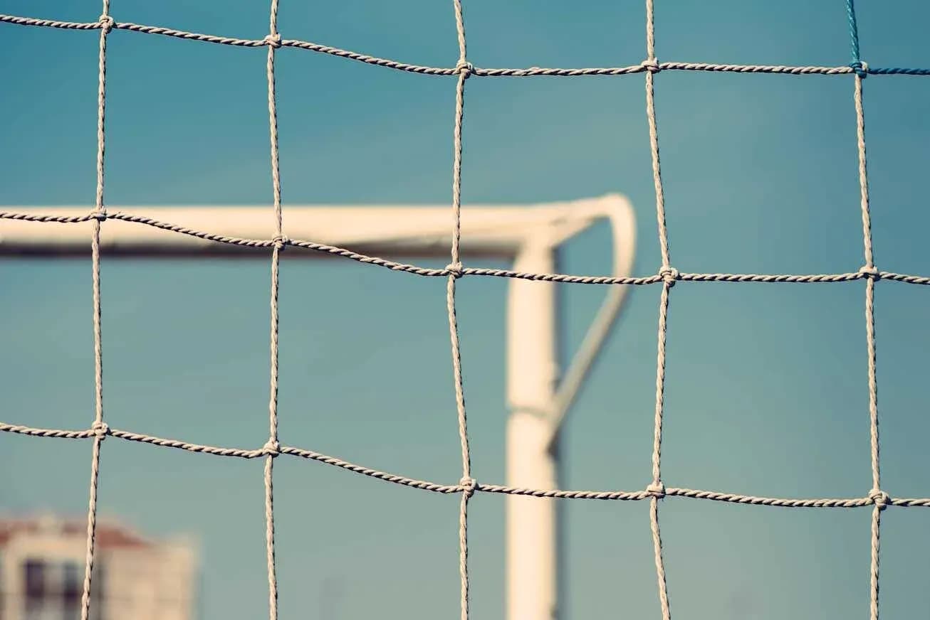 Close-up of a soccer goal net against blue sky