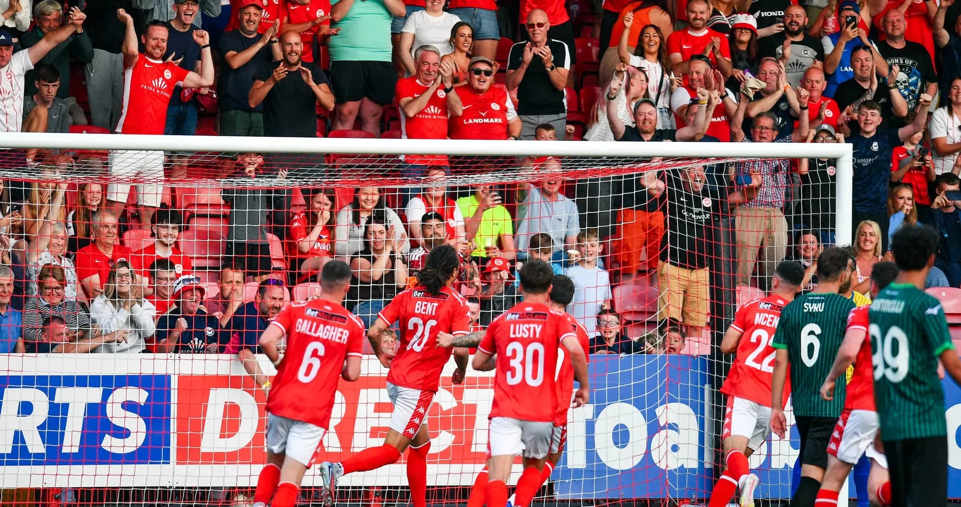 Larne players celebrating a goal with fans