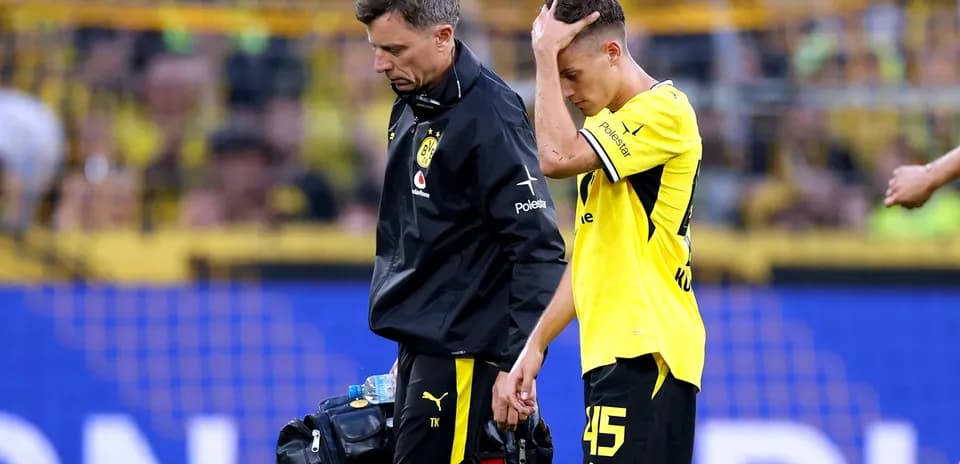 Player being assisted off the field by staff