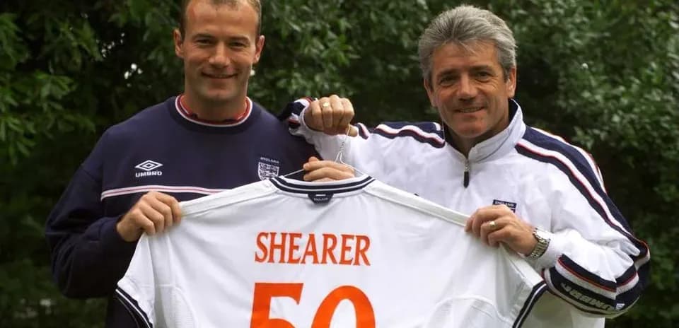 Two men holding a jersey with 'SHEARER 50'