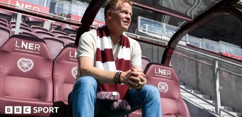 Manager sitting on bench in stadium with scarf