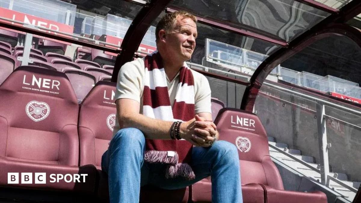 Manager sitting on bench in stadium with scarf