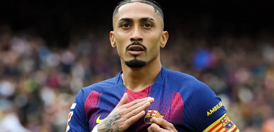 Player gesturing towards FC Barcelona crest on jersey
