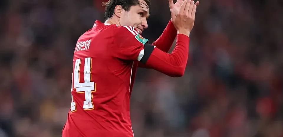 Player applauding fans in red jersey during match