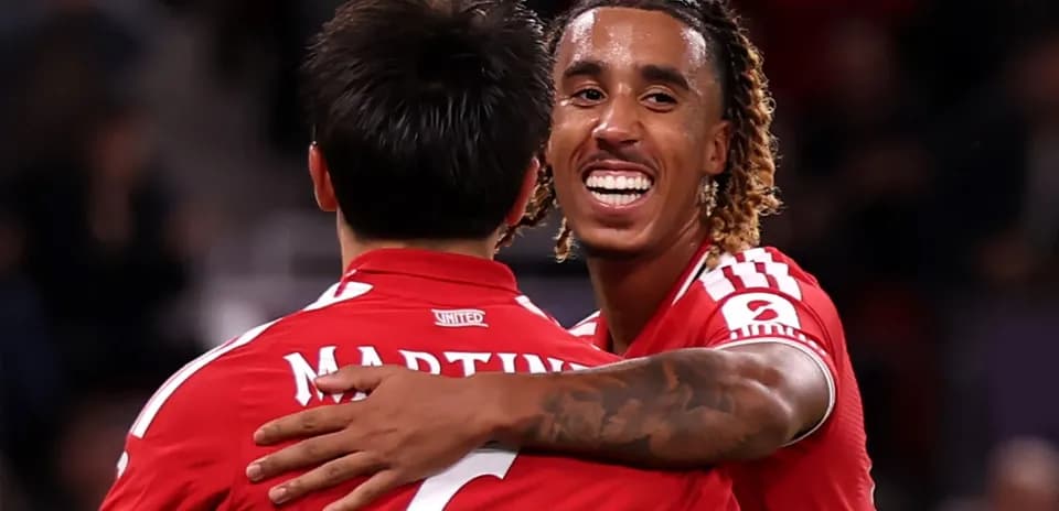 Two players celebrating in red jerseys after a goal