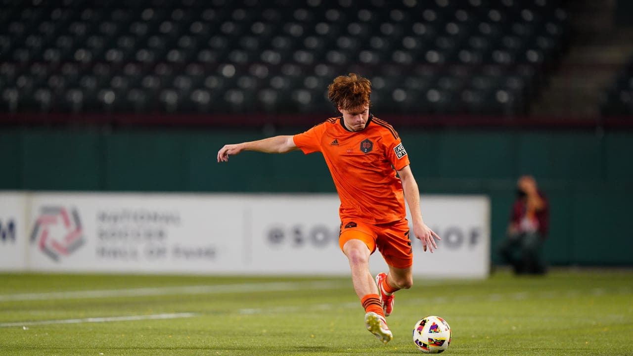 Player in orange kit kicking soccer ball