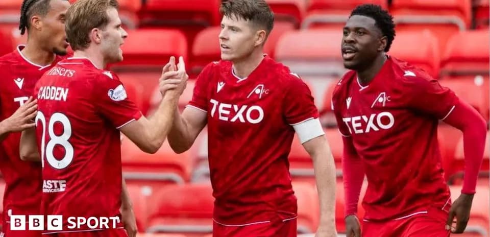 Players celebrating a goal in red team jerseys