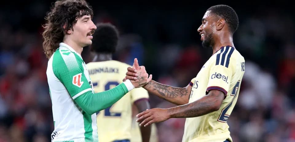 Two football players shaking hands on field
