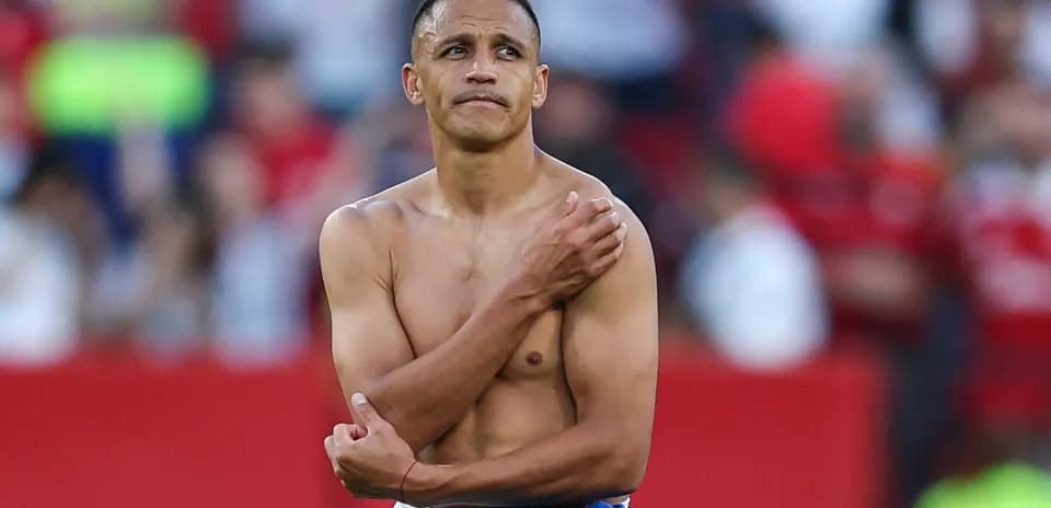 Player standing shirtless with blue shorts on field