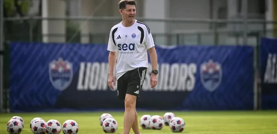 Coach walking on training pitch with soccer balls