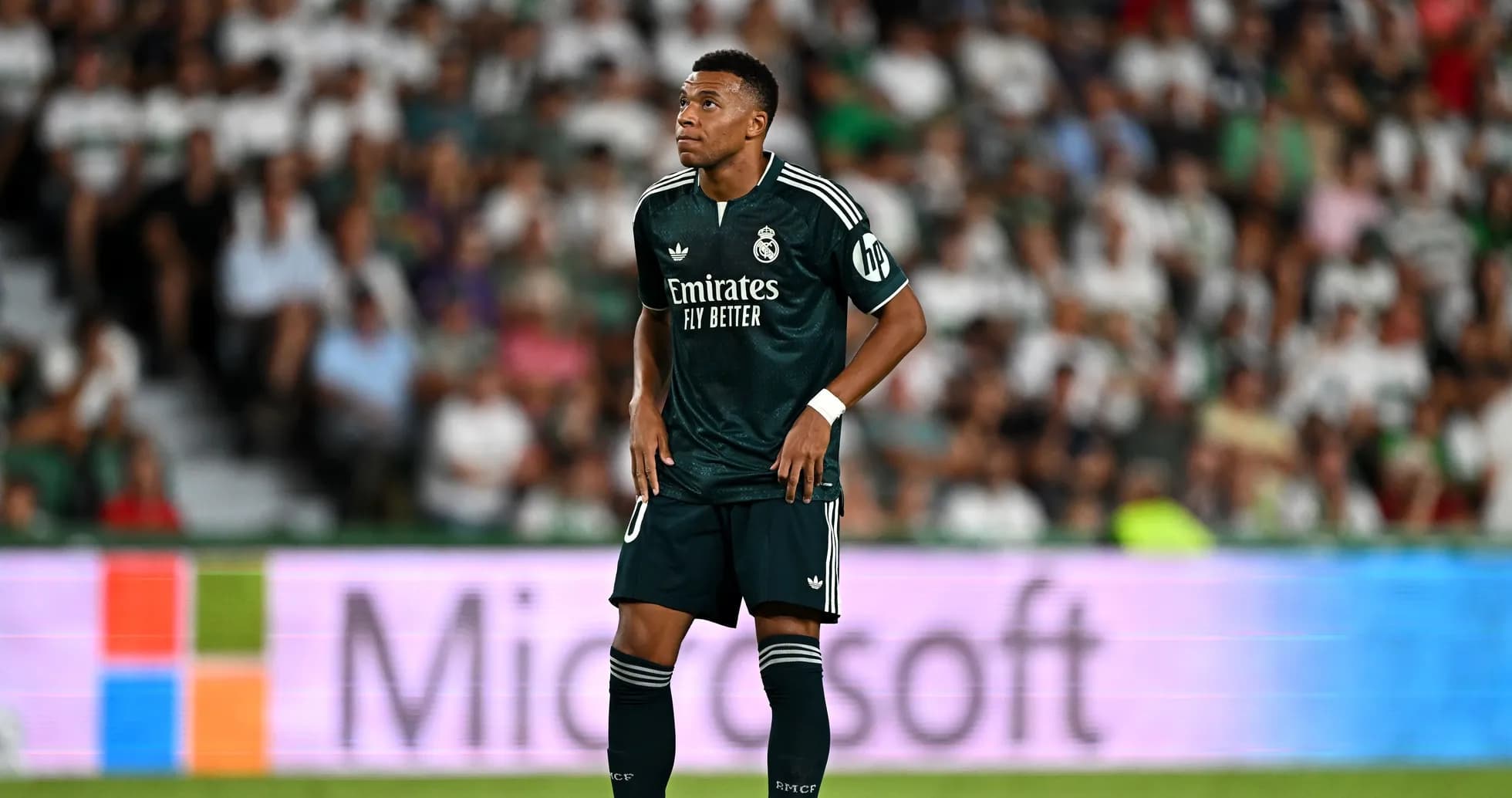 Player in green kit during match with fans in background