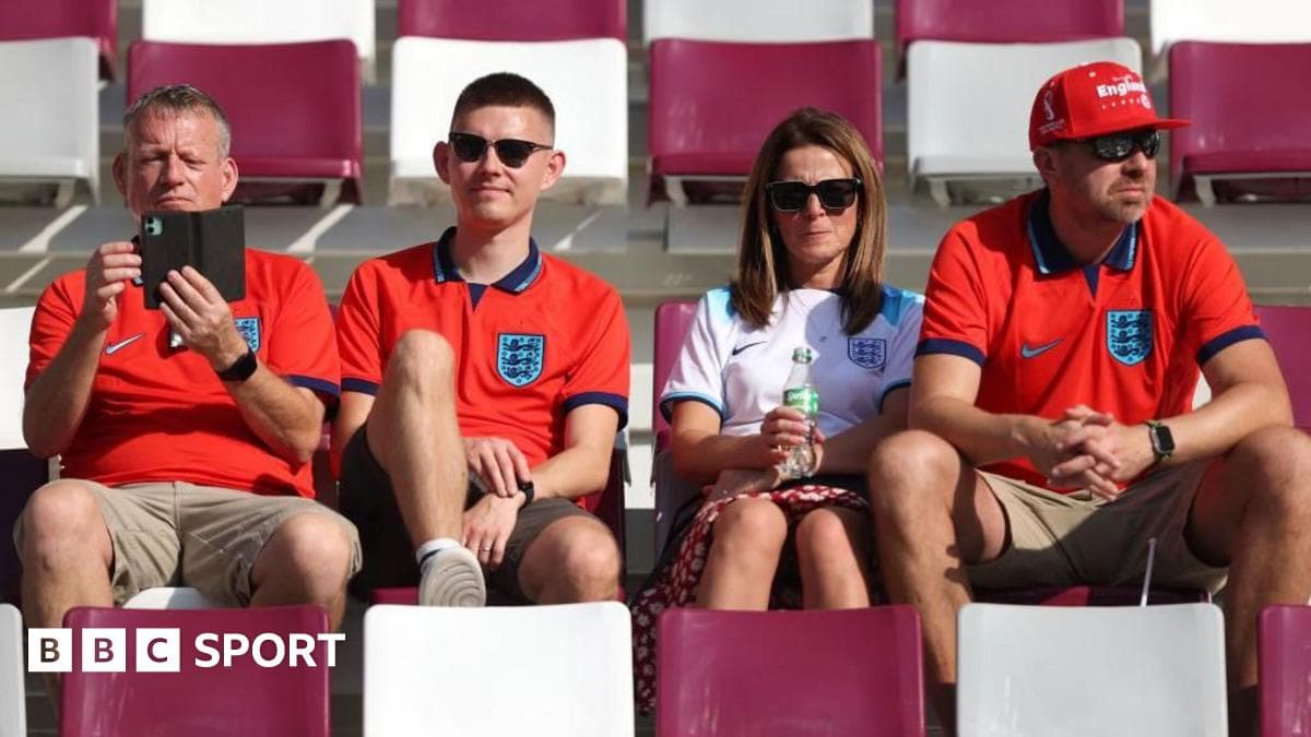 Fans in England jerseys sitting in stadium seats