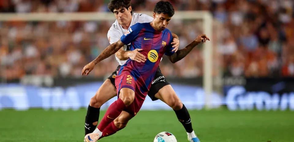 Barcelona player challenged by Valencia player during match