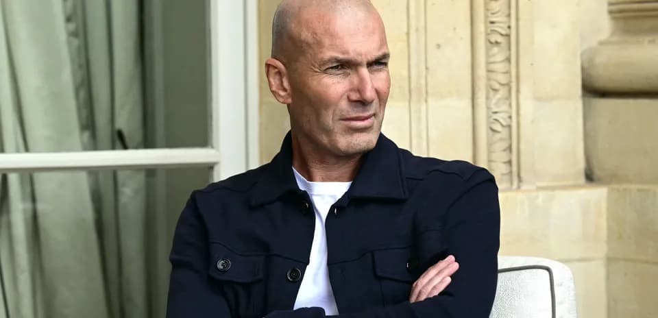 Man sitting with arms crossed, wearing dark jacket