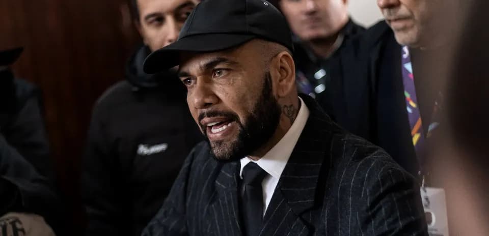 Man in suit speaking surrounded by onlookers