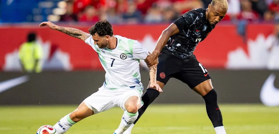 Two soccer players battling for the ball
