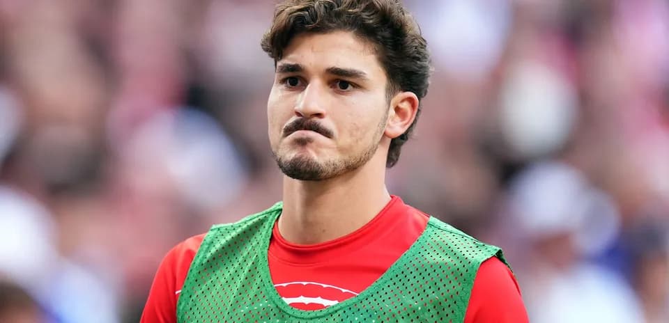 Player in green training vest on sidelines