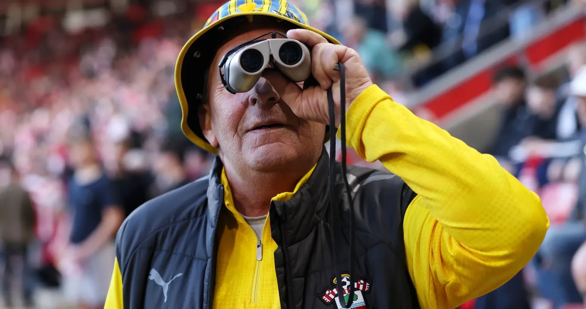 Fan wearing binoculars and team apparel at stadium