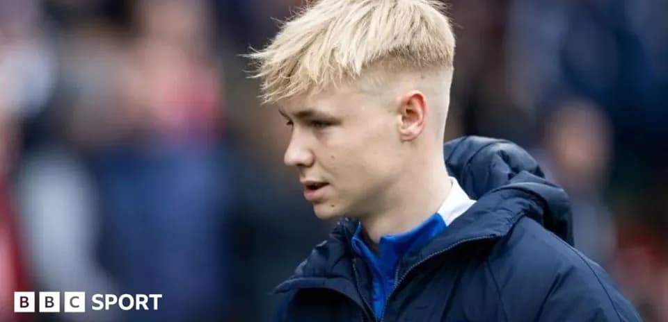 Player in blue jacket walking on pitch