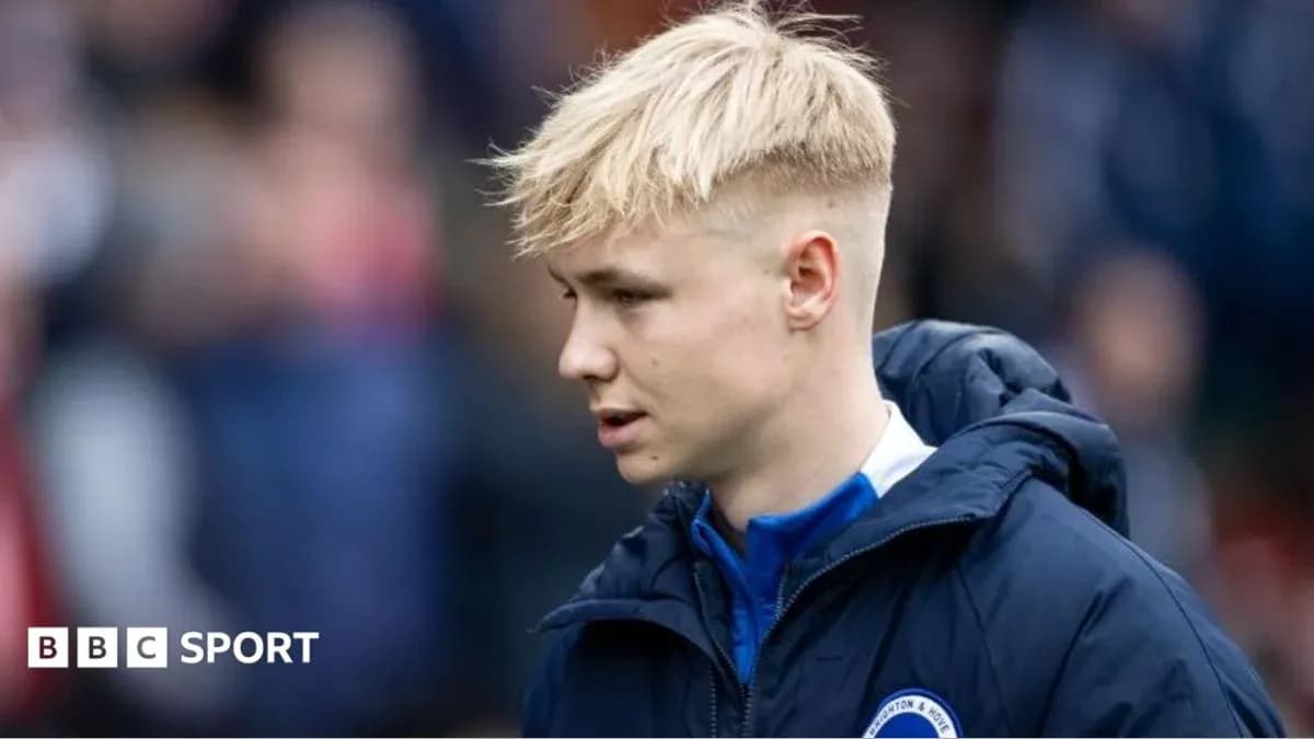 Player in blue jacket walking on pitch