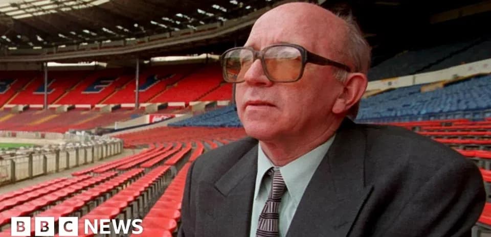 Man seated in empty stadium with red seats