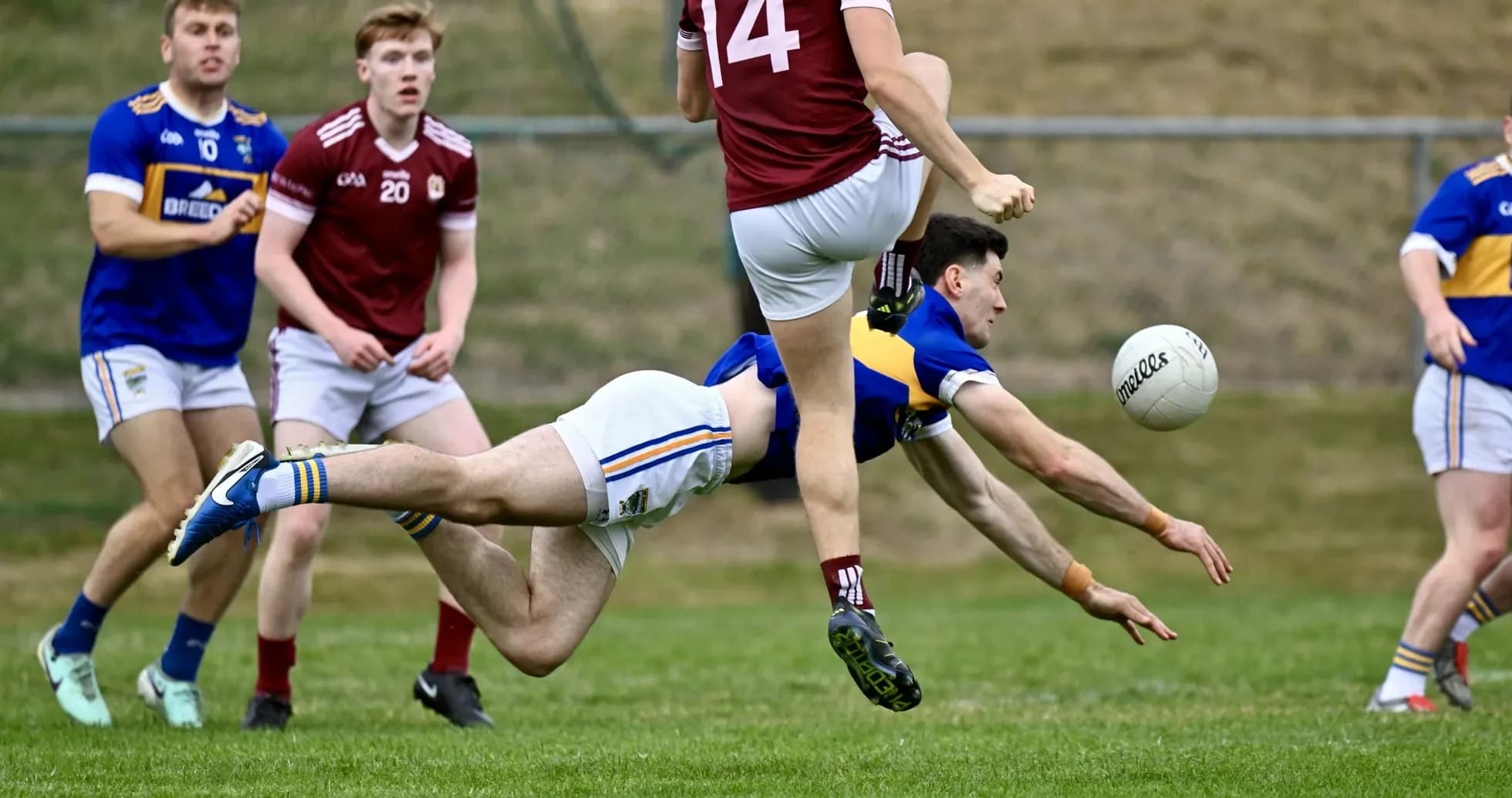 Player diving to catch a ball during Gaelic football match