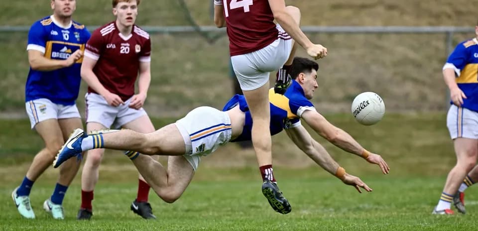 Player diving to catch a ball during Gaelic football match