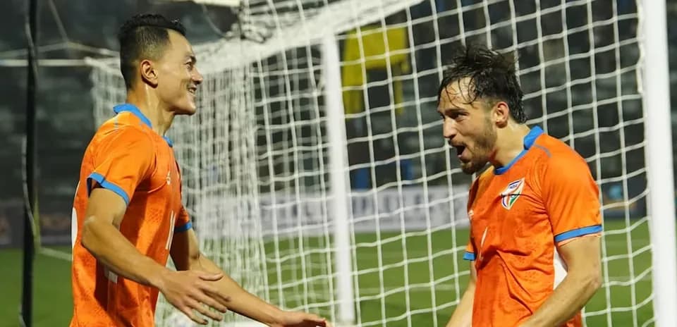 Players celebrating a goal in orange jerseys