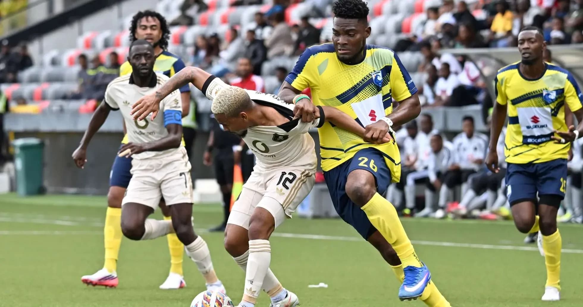 Orlando Pirates player challenged by La Cure Waves opponent