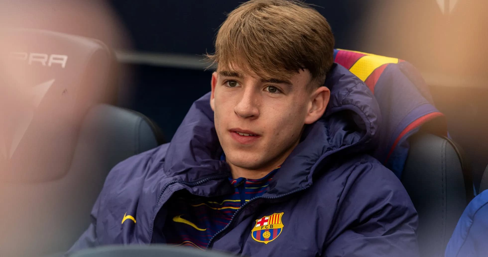 Player sitting on bench in Barcelona jacket
