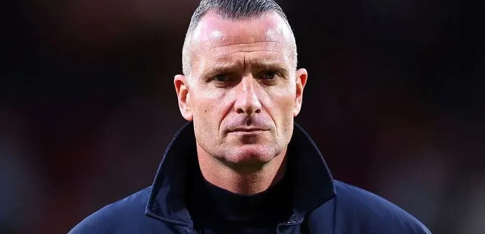Man in dark coat standing on football pitch