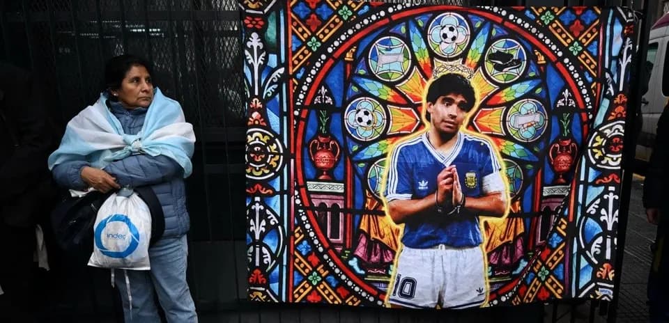 Woman in Argentina jersey beside mural of Maradona