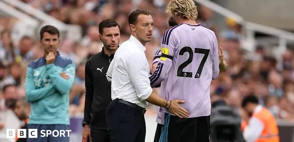 Coach speaking to goalkeeper during match substitution