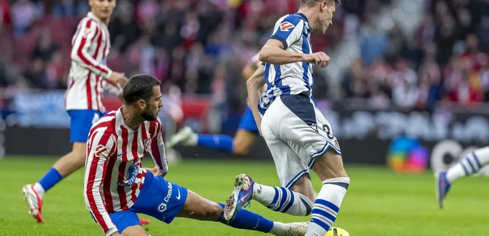 Real Sociedad player tackling Atletico Madrid opponent