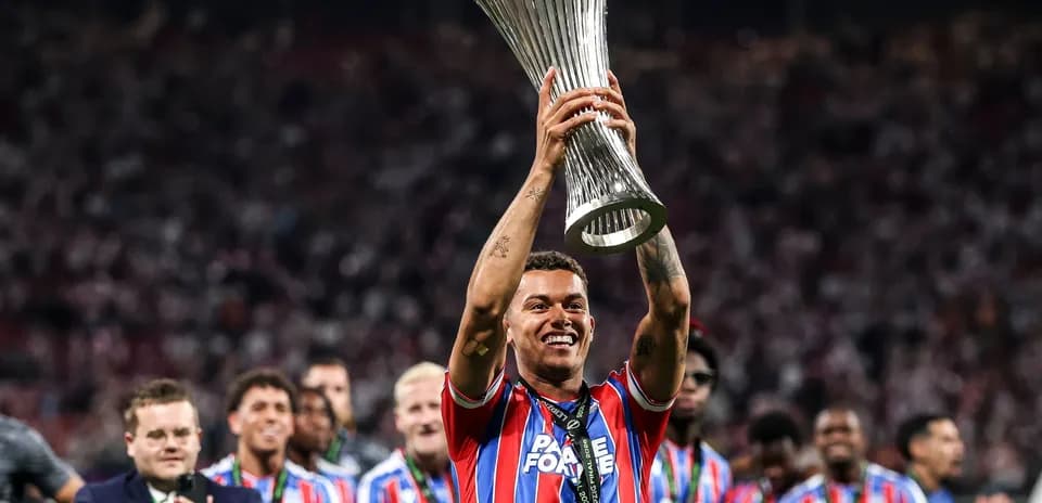 Player celebrating with trophy and teammates in stadium