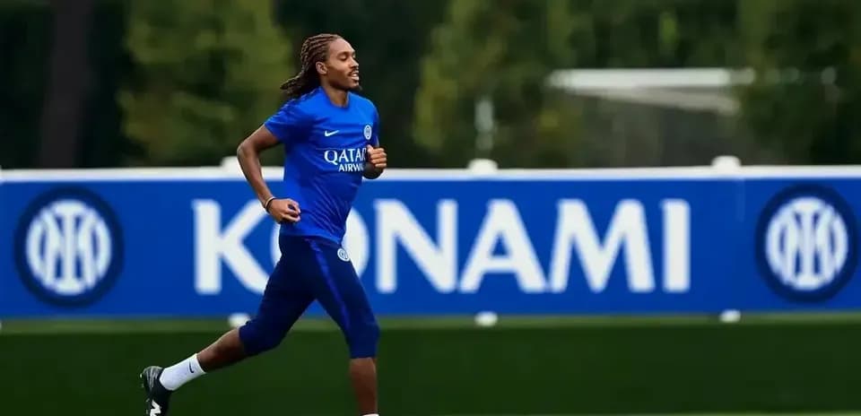 Player jogging on training pitch with team logo backdrop