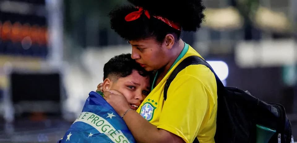 Woman holding child wrapped in Brazilian flag