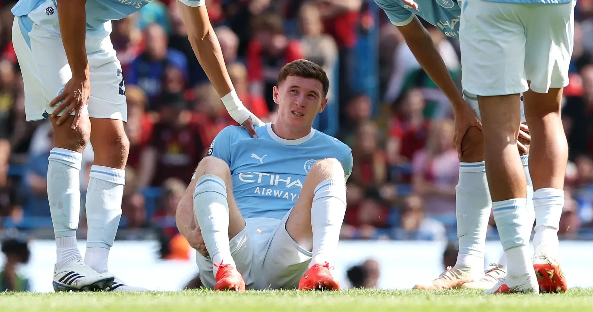 Player sitting on field with teammates assisting