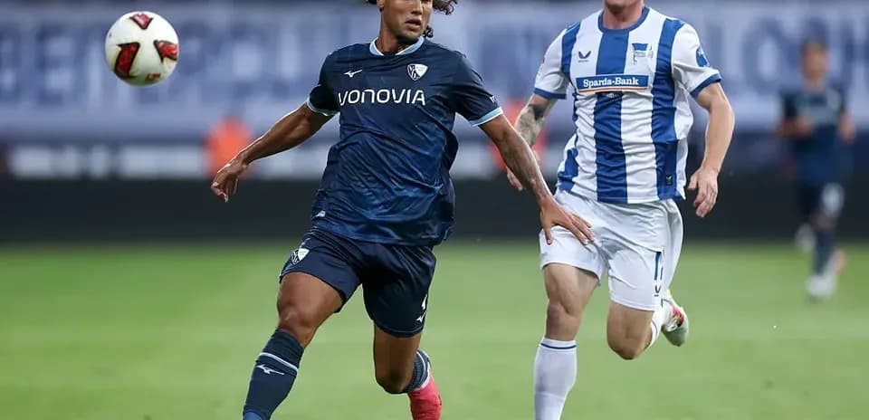 Player in blue chasing ball with opponent nearby