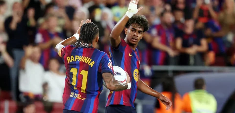 Two FC Barcelona players celebrating on the pitch
