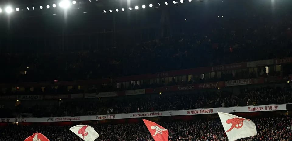 Arsenal fans waving flags in stadium crowd