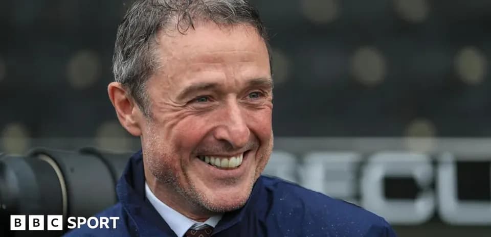 Smiling man in a blue jacket at stadium