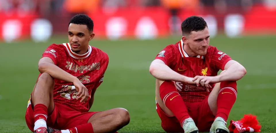 Two Liverpool players sitting on pitch after match