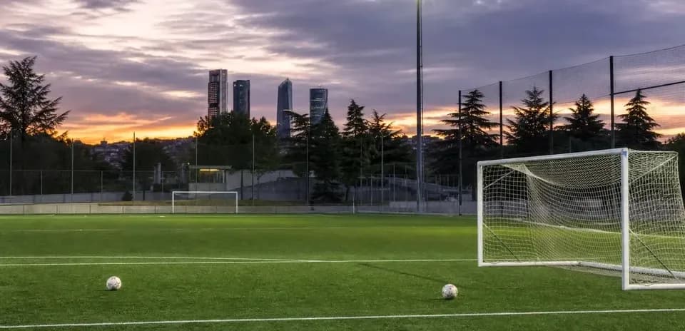 Soccer field with goal and city skyline at sunset