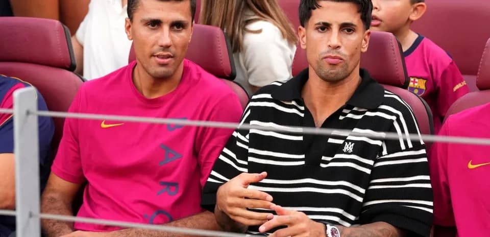 Two men seated in stadium wearing team apparel