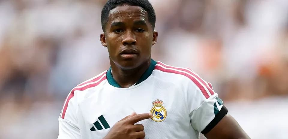 Player pointing at Real Madrid club logo on jersey