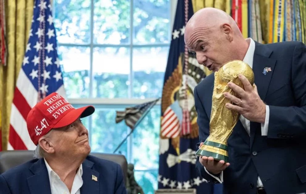 Person holding FIFA World Cup trophy with another seated