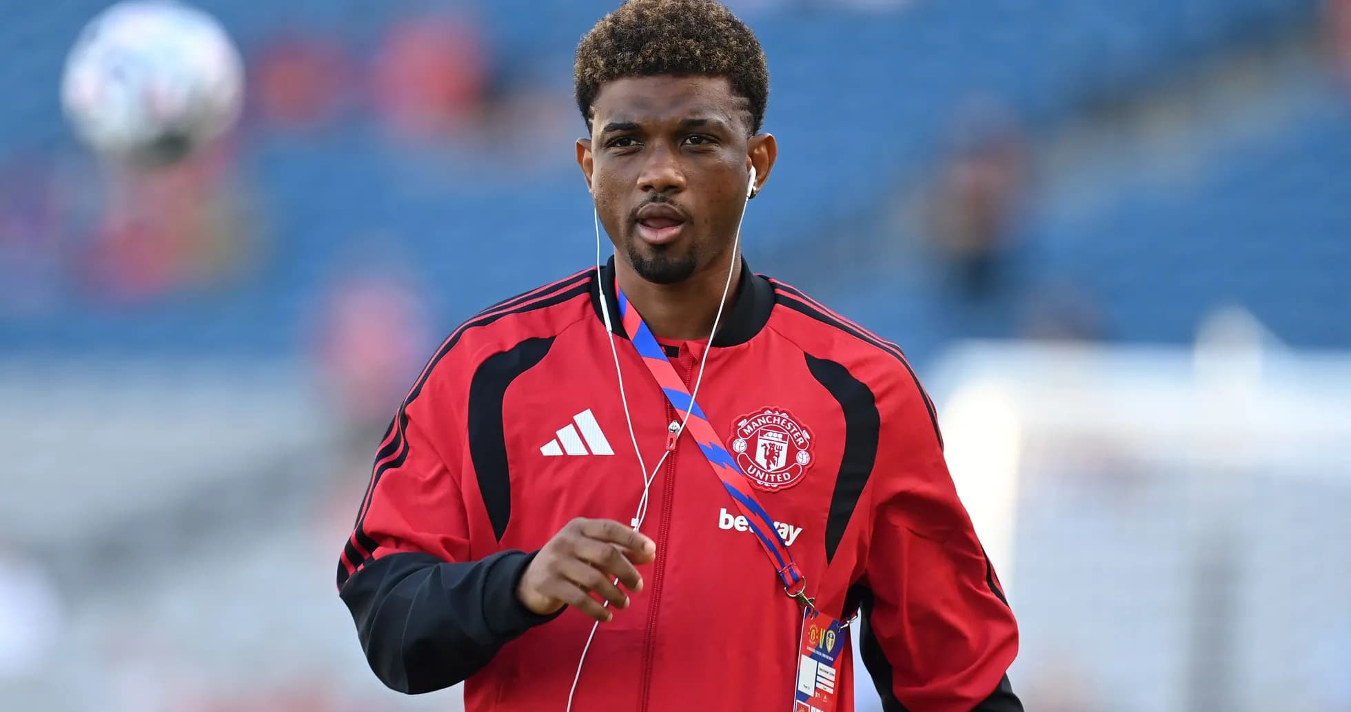 Player in Manchester United kit walking with headphones